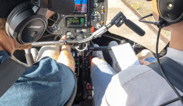 Ein Pilot erklärt dem Flugschüler in einem Helikopter das Cockpit
